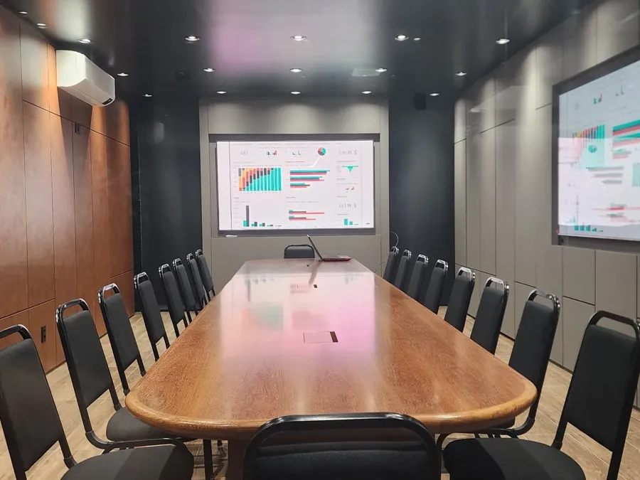 Sala com mesa executiva e TVs de 100 polegadas